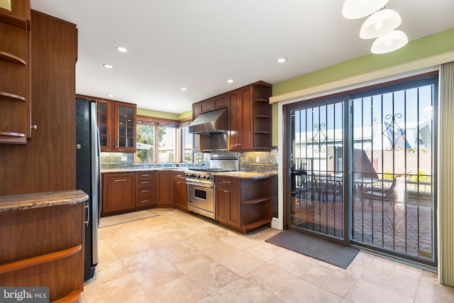 kitchen featuring light stone countertops, range hood, appliances with stainless steel finishes, tasteful backsplash, and light tile patterned flooring