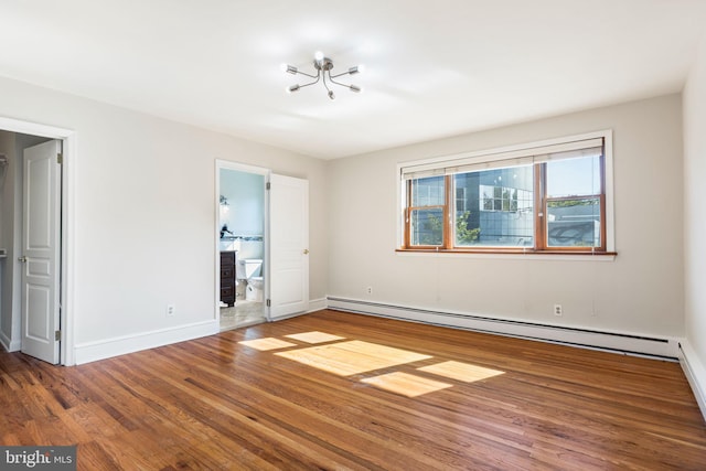 unfurnished bedroom featuring a baseboard heating unit, wood-type flooring, and connected bathroom