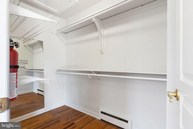 spacious closet featuring a baseboard heating unit and dark hardwood / wood-style flooring