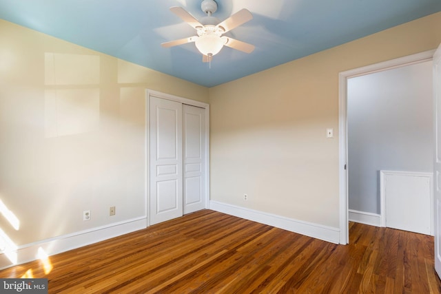 unfurnished bedroom with dark wood-type flooring, a closet, and ceiling fan