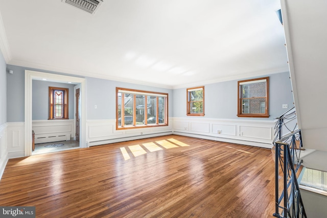 unfurnished living room with a wealth of natural light, a baseboard radiator, and wood-type flooring