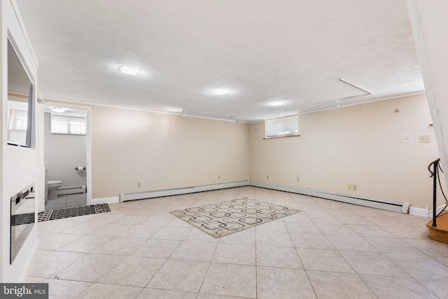 basement featuring light tile patterned floors, a textured ceiling, and a baseboard radiator