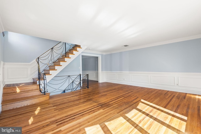 unfurnished living room featuring wood-type flooring and crown molding