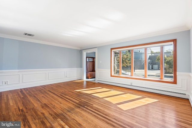 unfurnished room featuring crown molding, baseboard heating, and hardwood / wood-style floors