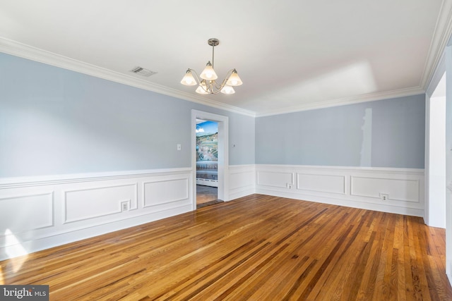 empty room featuring ornamental molding, a baseboard radiator, hardwood / wood-style floors, and an inviting chandelier