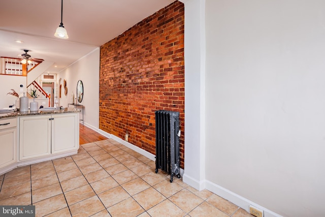 kitchen featuring white cabinets, hanging light fixtures, stone countertops, ceiling fan, and radiator