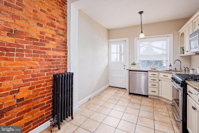 kitchen with white cabinetry, stainless steel appliances, radiator heating unit, sink, and light stone countertops