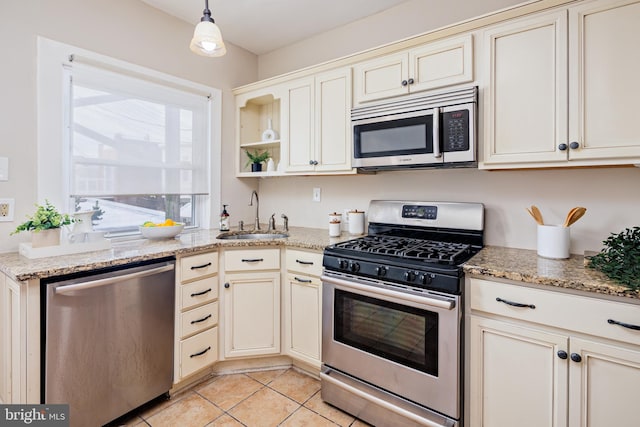 kitchen featuring decorative light fixtures, sink, cream cabinets, appliances with stainless steel finishes, and light tile patterned flooring