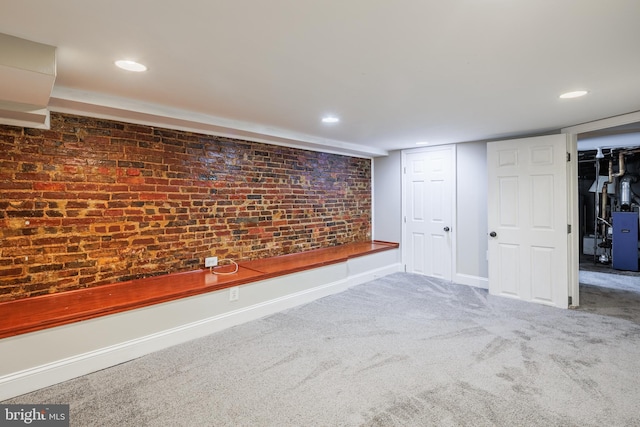 basement featuring carpet and brick wall