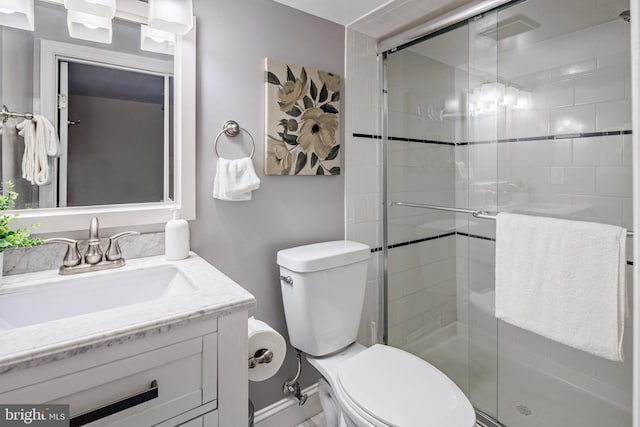 bathroom featuring toilet, a shower with door, and vanity