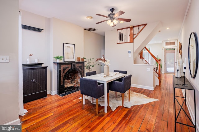 dining space with hardwood / wood-style floors, ceiling fan, and a tile fireplace