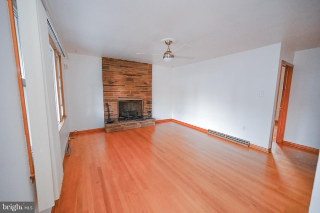 unfurnished living room featuring light hardwood / wood-style flooring, ceiling fan, a stone fireplace, and a baseboard radiator