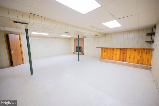 basement featuring wood walls and a drop ceiling