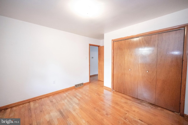 unfurnished bedroom with light hardwood / wood-style flooring and a closet