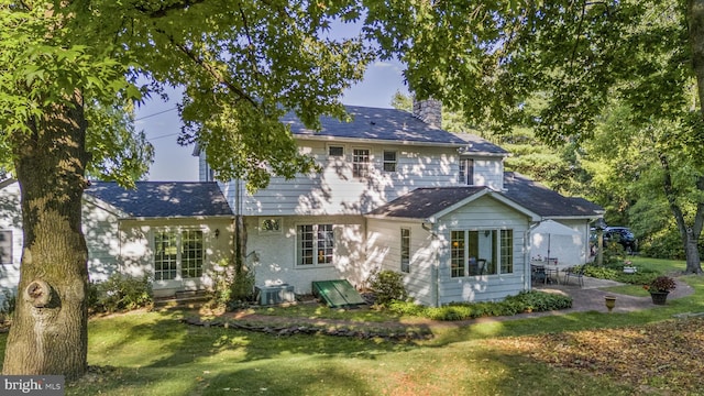 back of house with a lawn and a patio