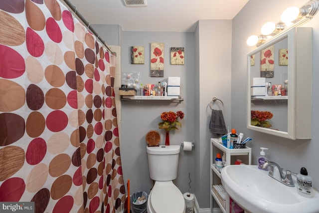 bathroom with curtained shower, toilet, and sink