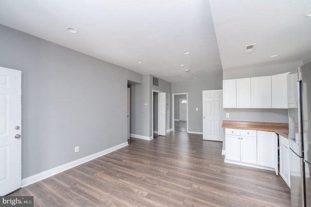 kitchen with butcher block countertops, stainless steel fridge, white cabinetry, and dark wood-type flooring