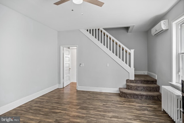 stairs with hardwood / wood-style floors, ceiling fan, radiator heating unit, and an AC wall unit