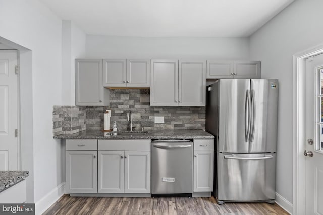 kitchen featuring appliances with stainless steel finishes, tasteful backsplash, hardwood / wood-style flooring, and sink