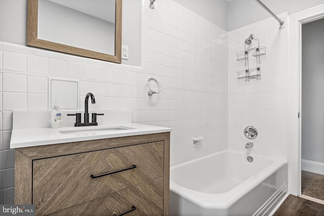 bathroom with tiled shower / bath combo, vanity, tile walls, and wood-type flooring