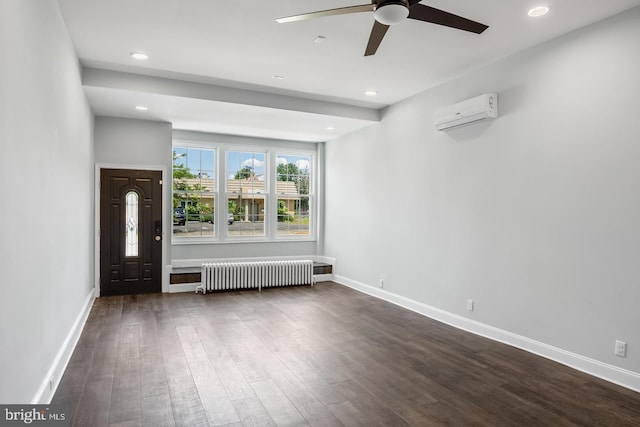 unfurnished living room featuring radiator heating unit, a wall unit AC, ceiling fan, and dark hardwood / wood-style floors