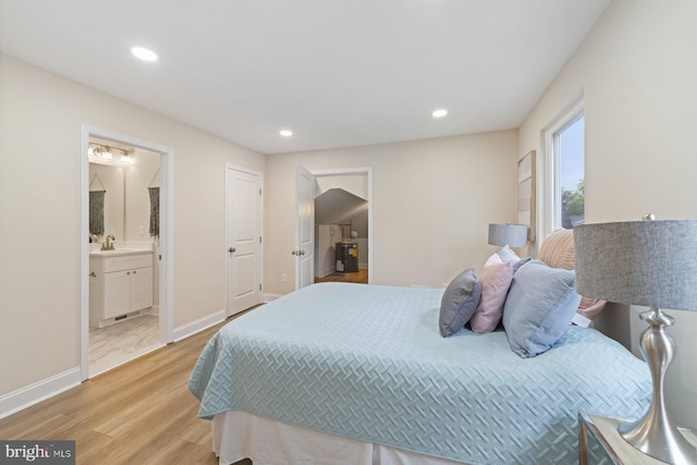 bedroom featuring light wood-type flooring, ensuite bathroom, and sink