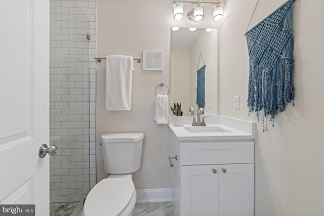 bathroom with tiled shower, vanity, and toilet