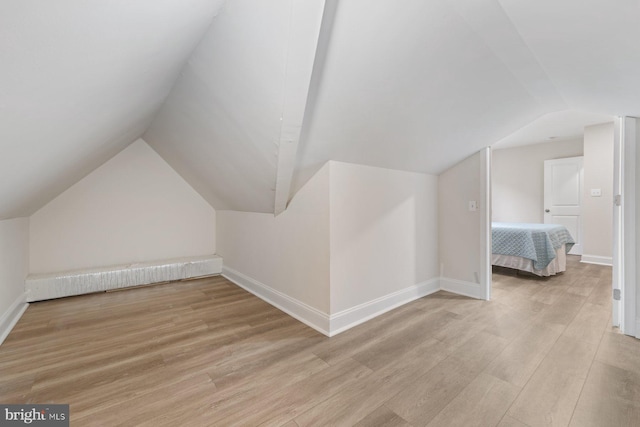 additional living space with light hardwood / wood-style flooring and vaulted ceiling