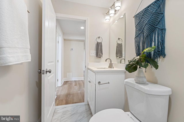 bathroom with wood-type flooring, vanity, and toilet