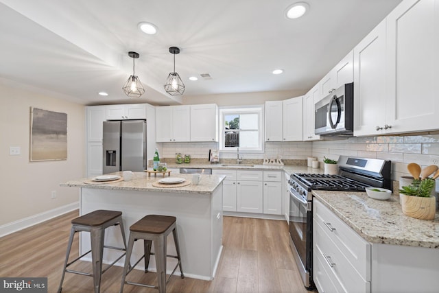 kitchen with appliances with stainless steel finishes, white cabinetry, a center island, and sink