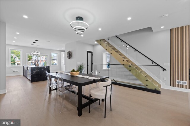 dining area with light wood-type flooring and an inviting chandelier