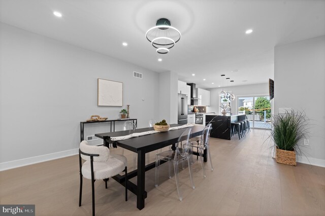 dining room with light wood-type flooring and an inviting chandelier