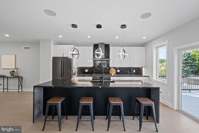 kitchen featuring white cabinets, stainless steel fridge, a kitchen breakfast bar, and dark stone counters