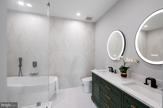 bathroom with tile patterned floors, toilet, a bath, tile walls, and vanity