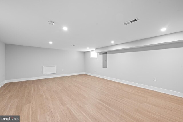 basement with light wood-type flooring and electric panel