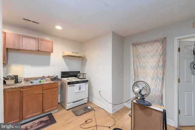 kitchen with light hardwood / wood-style floors, exhaust hood, white range with gas cooktop, and sink