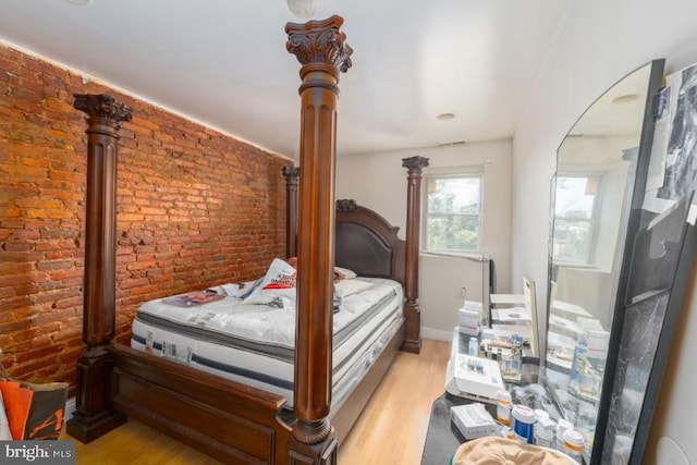 bedroom with brick wall and light wood-type flooring