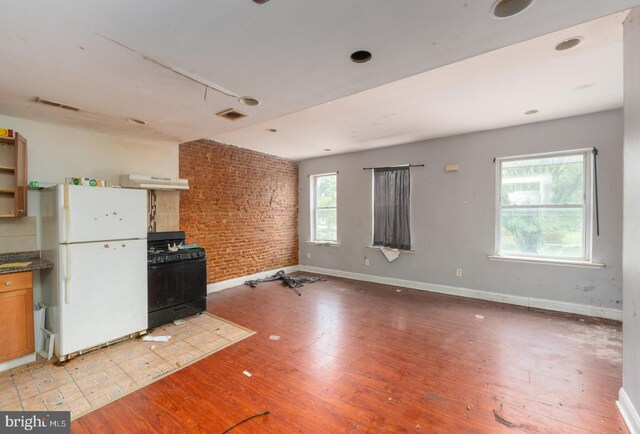 kitchen with plenty of natural light, black range with gas cooktop, light hardwood / wood-style flooring, and white refrigerator