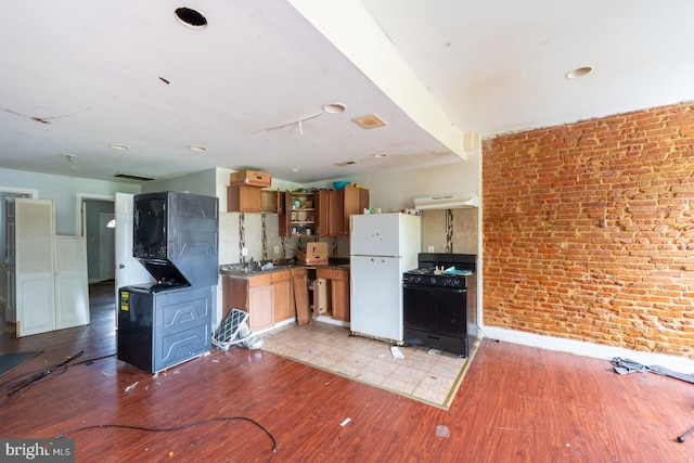 kitchen featuring light hardwood / wood-style flooring, black appliances, brick wall, and range hood