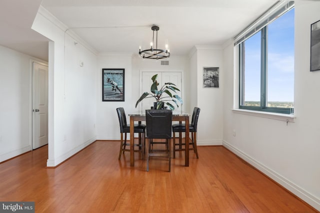 dining area featuring ornamental molding, hardwood / wood-style flooring, and an inviting chandelier