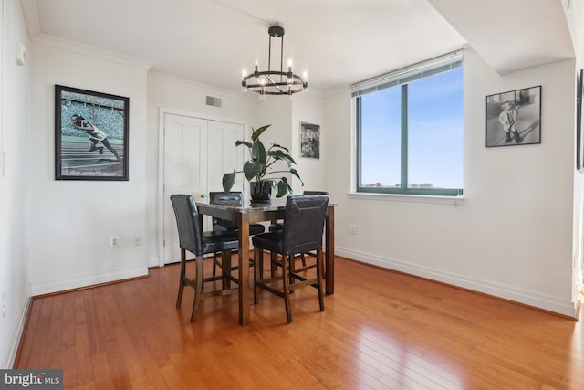 dining area with ornamental molding, wood-type flooring, and a notable chandelier