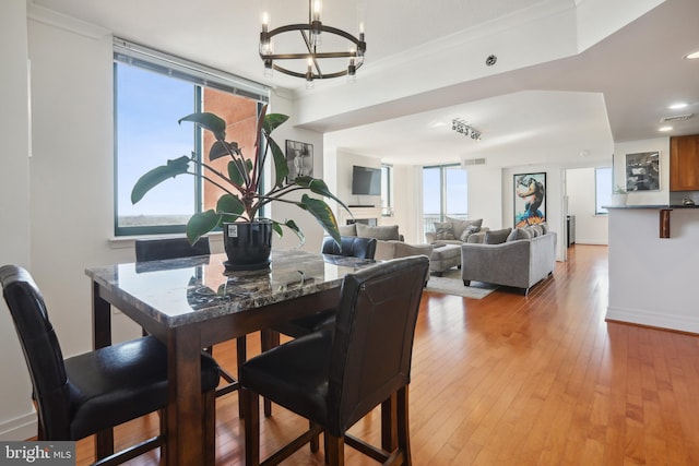 dining space with ornamental molding, a notable chandelier, and light wood-type flooring