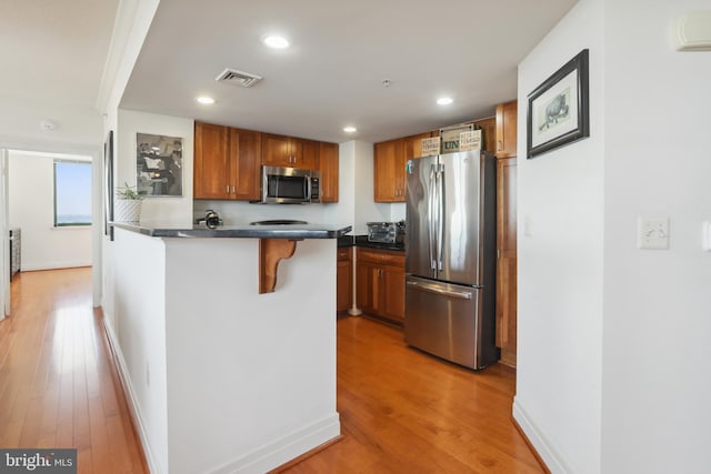 kitchen featuring light wood-type flooring, stainless steel appliances, and a kitchen breakfast bar