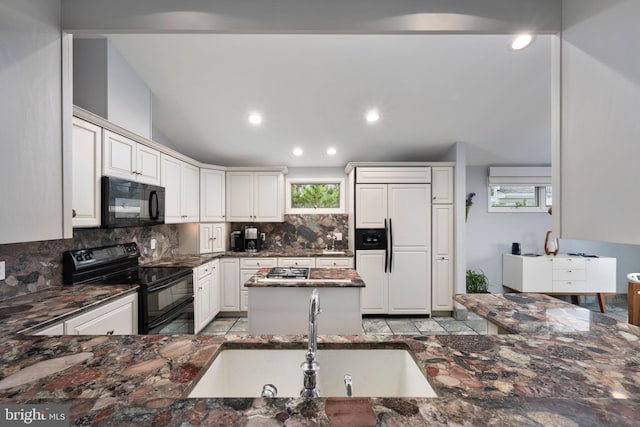 kitchen with tasteful backsplash, white cabinets, black appliances, dark stone counters, and sink