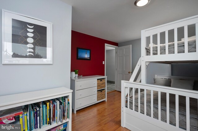 bedroom with wood-type flooring and a crib