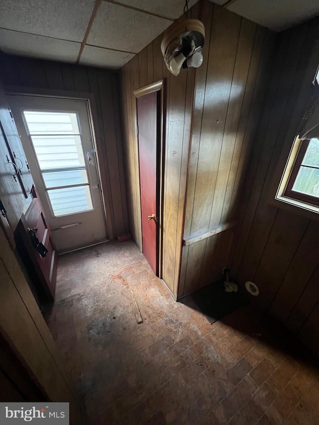 interior space featuring plenty of natural light, wood walls, and a drop ceiling