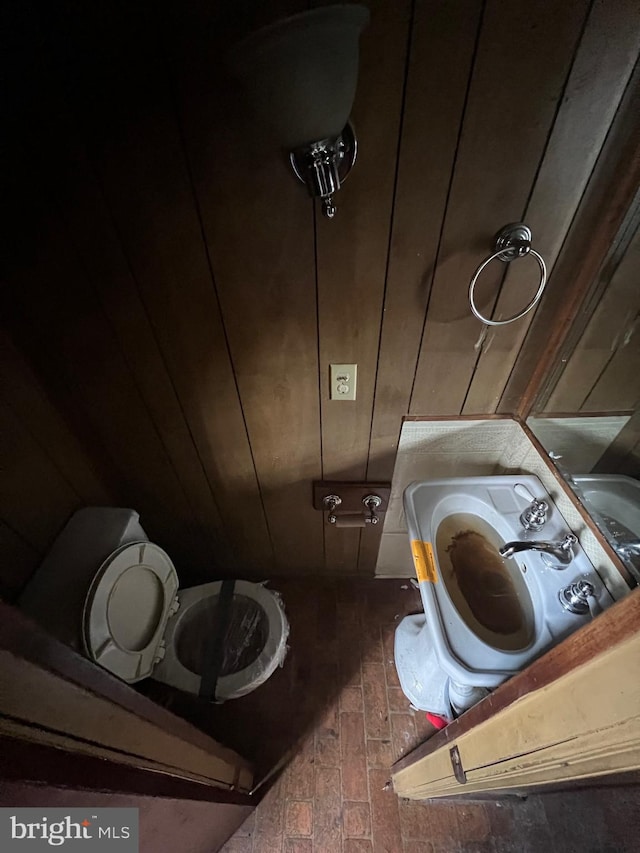 bathroom with toilet and wood walls