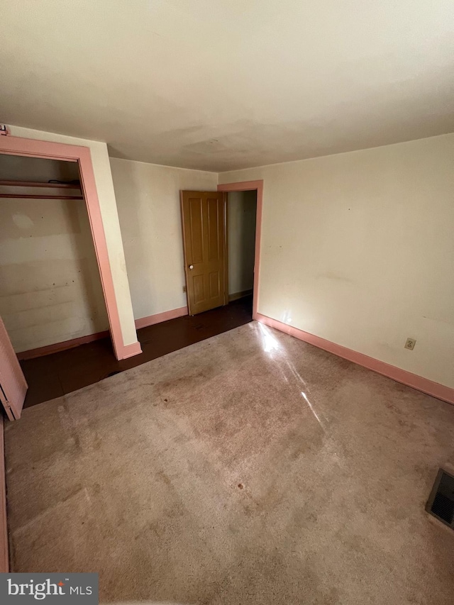 unfurnished bedroom featuring a closet and dark colored carpet