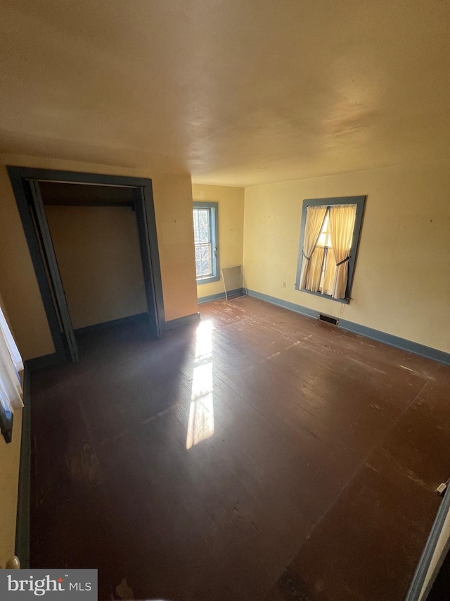 unfurnished bedroom with dark wood-type flooring and a closet