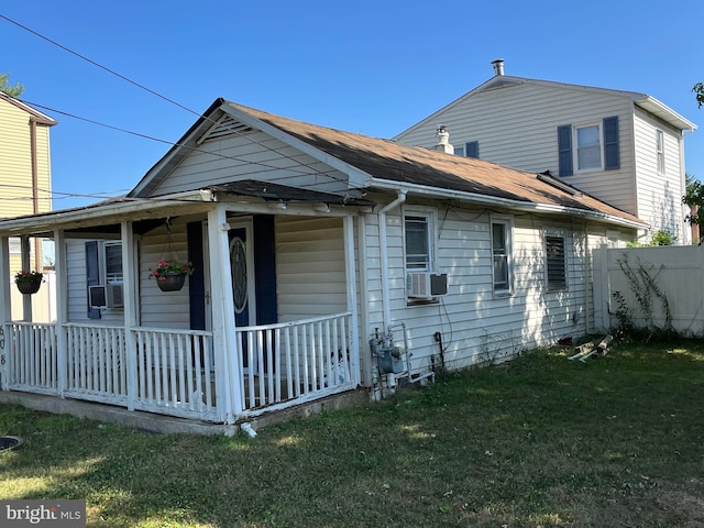 bungalow-style home featuring cooling unit, a front yard, and covered porch